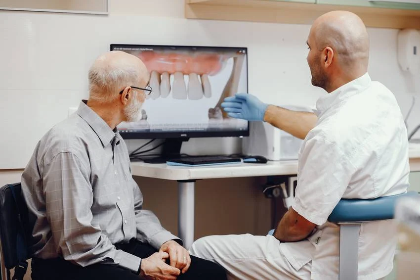 Un dentiste montrant à son patient les résultats après avoir reçu un traitement sur 4 implants en Albanie