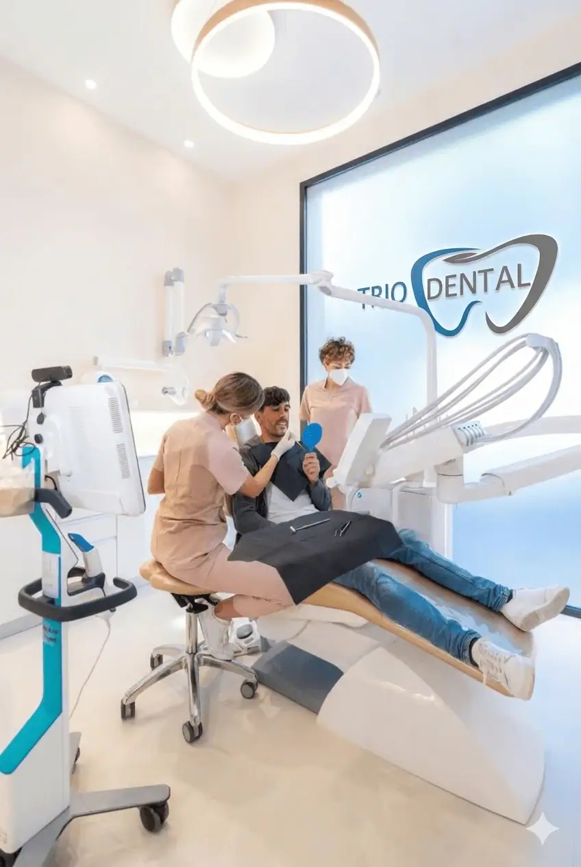 Un dentista esamina un paziente sorridente in una clinica moderna con attrezzature dentali e il marchio Trio Dental.