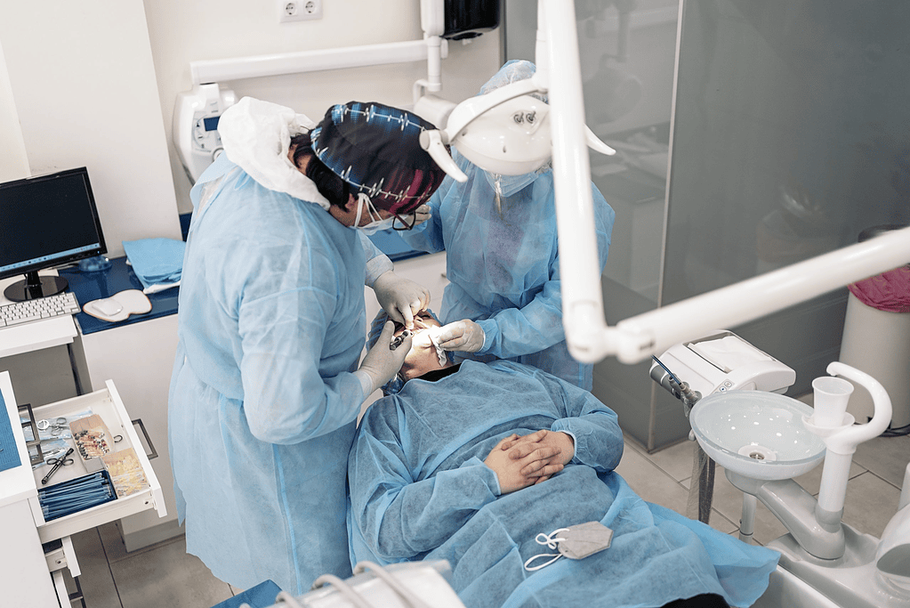Dentistas con bata realizando una intervención dental a un paciente en una clínica moderna.