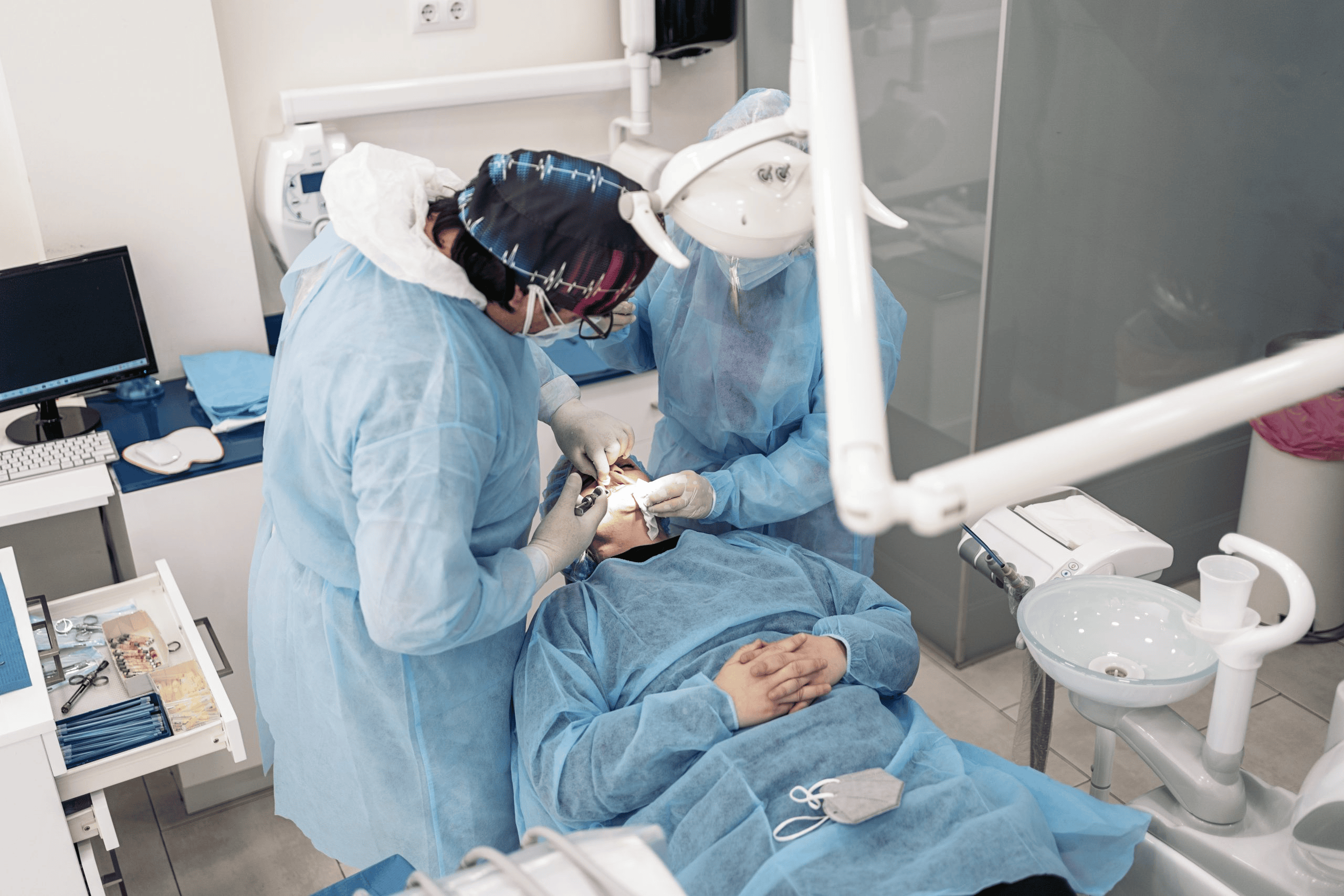 Dentists in scrubs performing a dental procedure on a patient in a modern clinic setting.