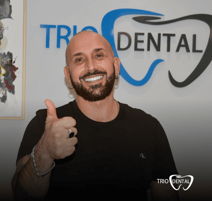 Un uomo sorridente fa il pollice in su alla Trio Dental, mostrando denti sani e soddisfazione per i servizi dentistici.