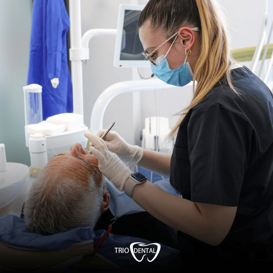 Un dentista esegue un controllo dentale su un paziente presso la clinica Trio Dental. Assistenza dentistica professionale in corso.