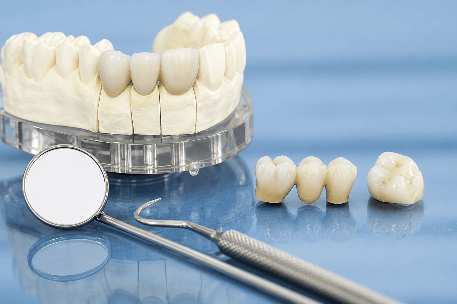 Corone dentali e strumenti su sfondo blu, che mostrano il restauro dei denti e gli elementi essenziali per l'igiene orale.