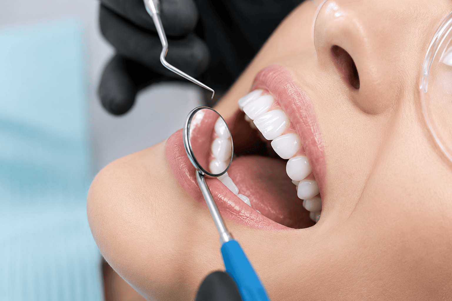 Primer plano de un chequeo dental con un dentista usando un espejo y una sonda para examinar los dientes de un paciente.