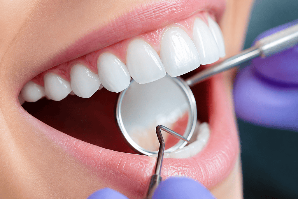 Primer plano de un chequeo dental que muestra las herramientas de un dentista examinando dientes y encías sanos y blancos.