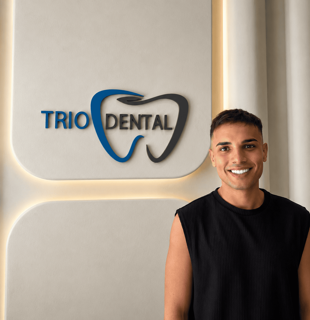 Hombre sonriendo frente al logo de Trio Dental, mostrando el diseño interior y la marca de una clínica dental moderna.