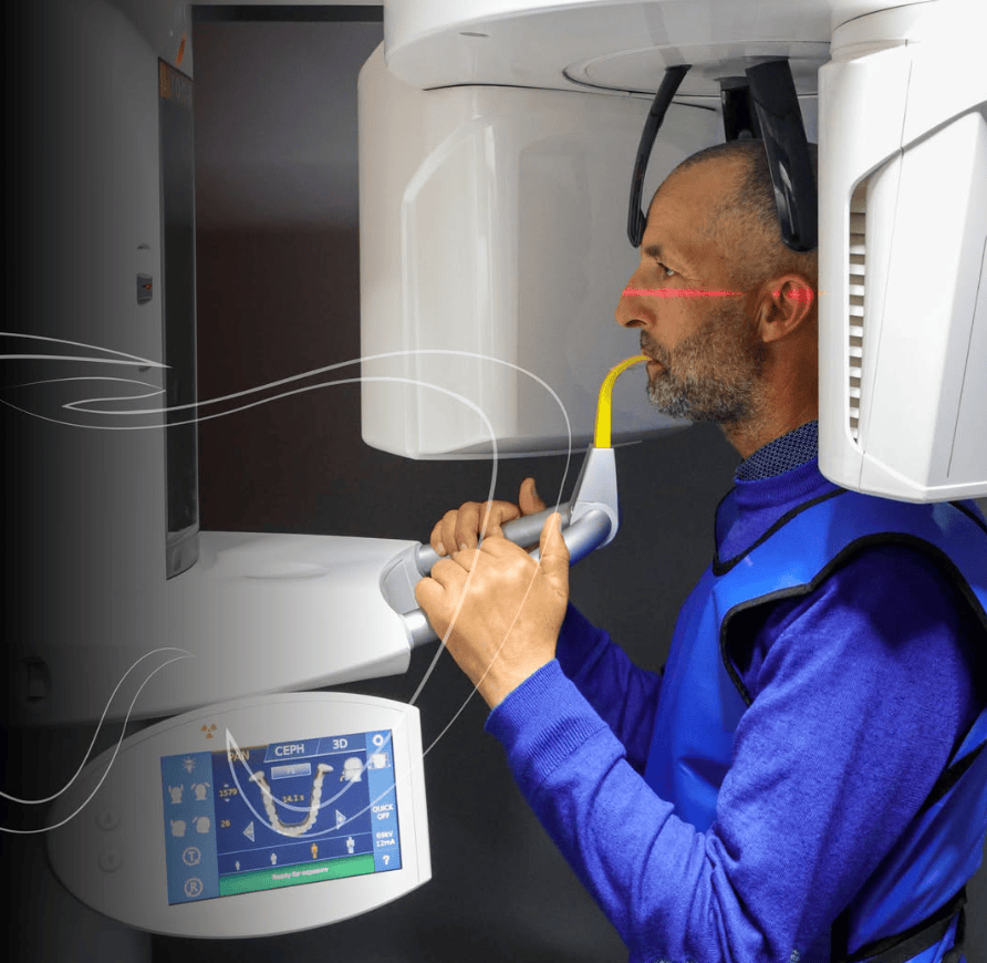 Man undergoing dental X-ray scan in modern imaging machine, wearing protective vest, side profile view.