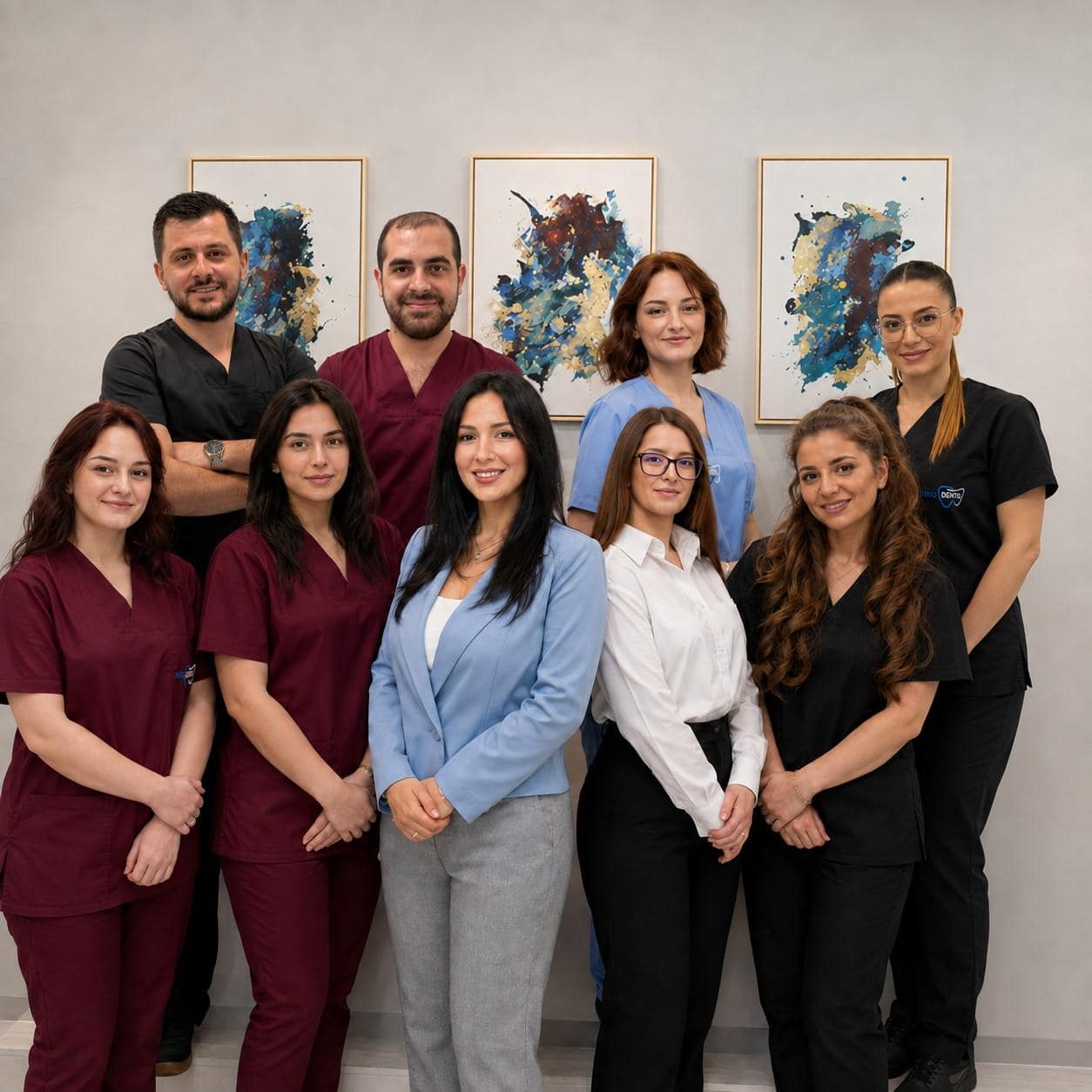 Team of medical professionals in uniforms and business attire standing in front of abstract art.