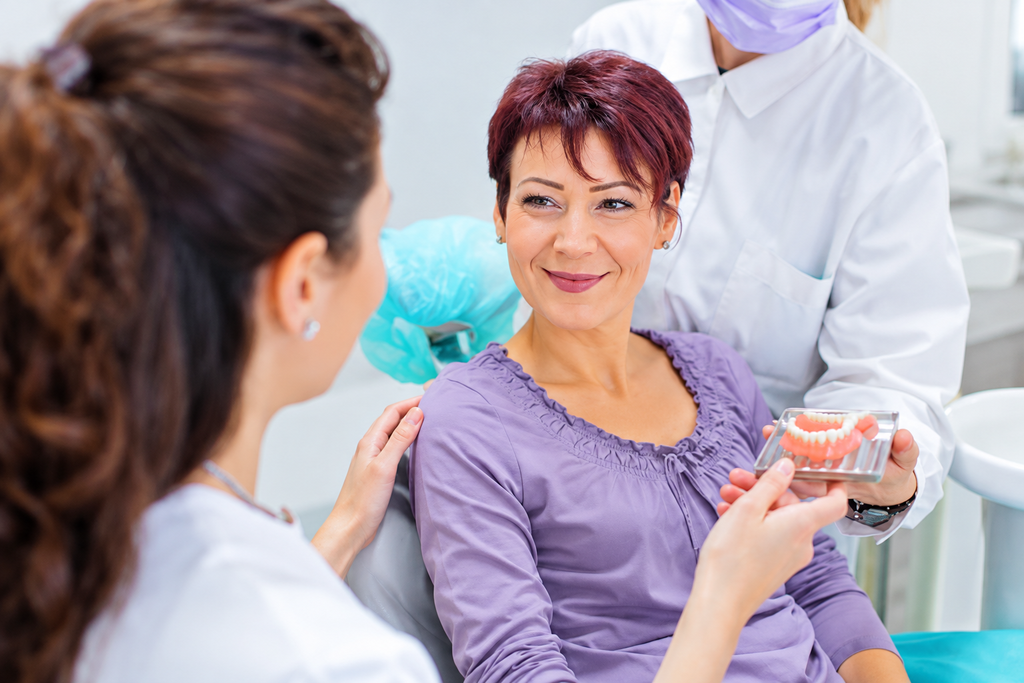Dentist showing patient dental options in clinic, promoting oral health and hygiene with supportive consultation.